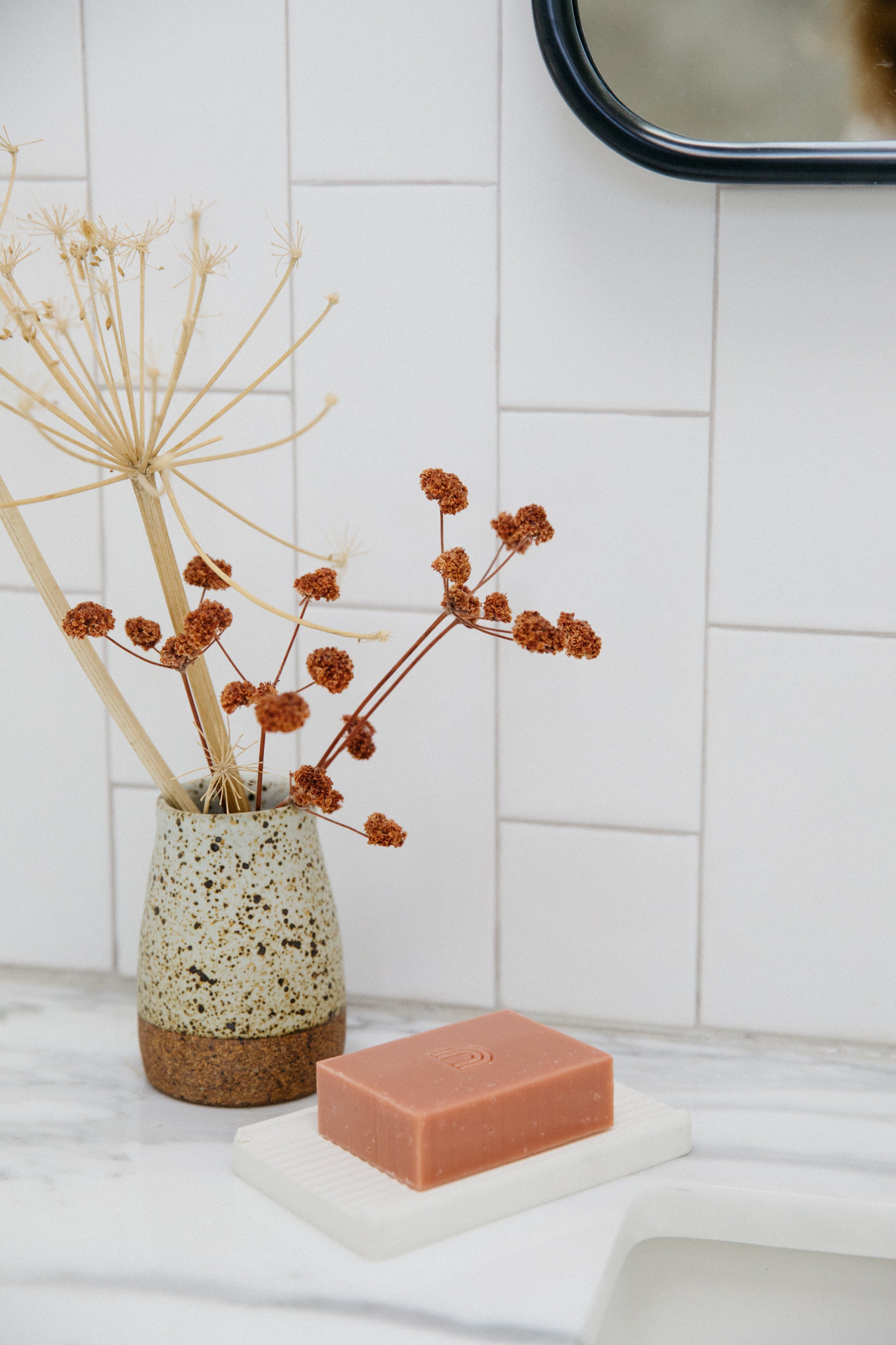 A photo of our Body Bar and Soap Dish at a sink next to a flower vase