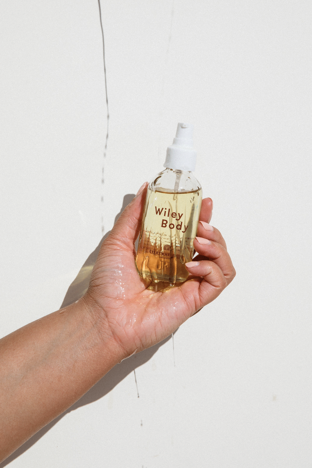 A gif of a brown arm holding a glass bottle with oil in it that reads "Everywhere Oil" and movement shows oil falling on bottle