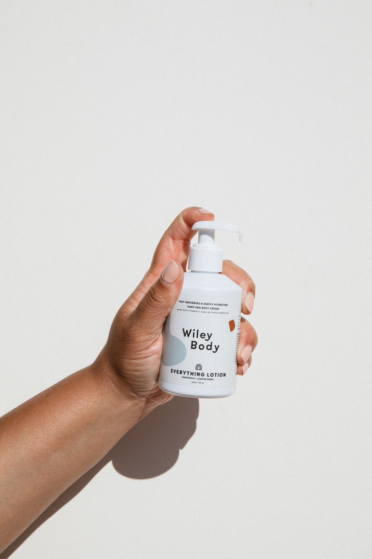 A brown hand holding a white bottle that has a label saying "Everything Lotion" and GIF shows it pumping out of the bottle