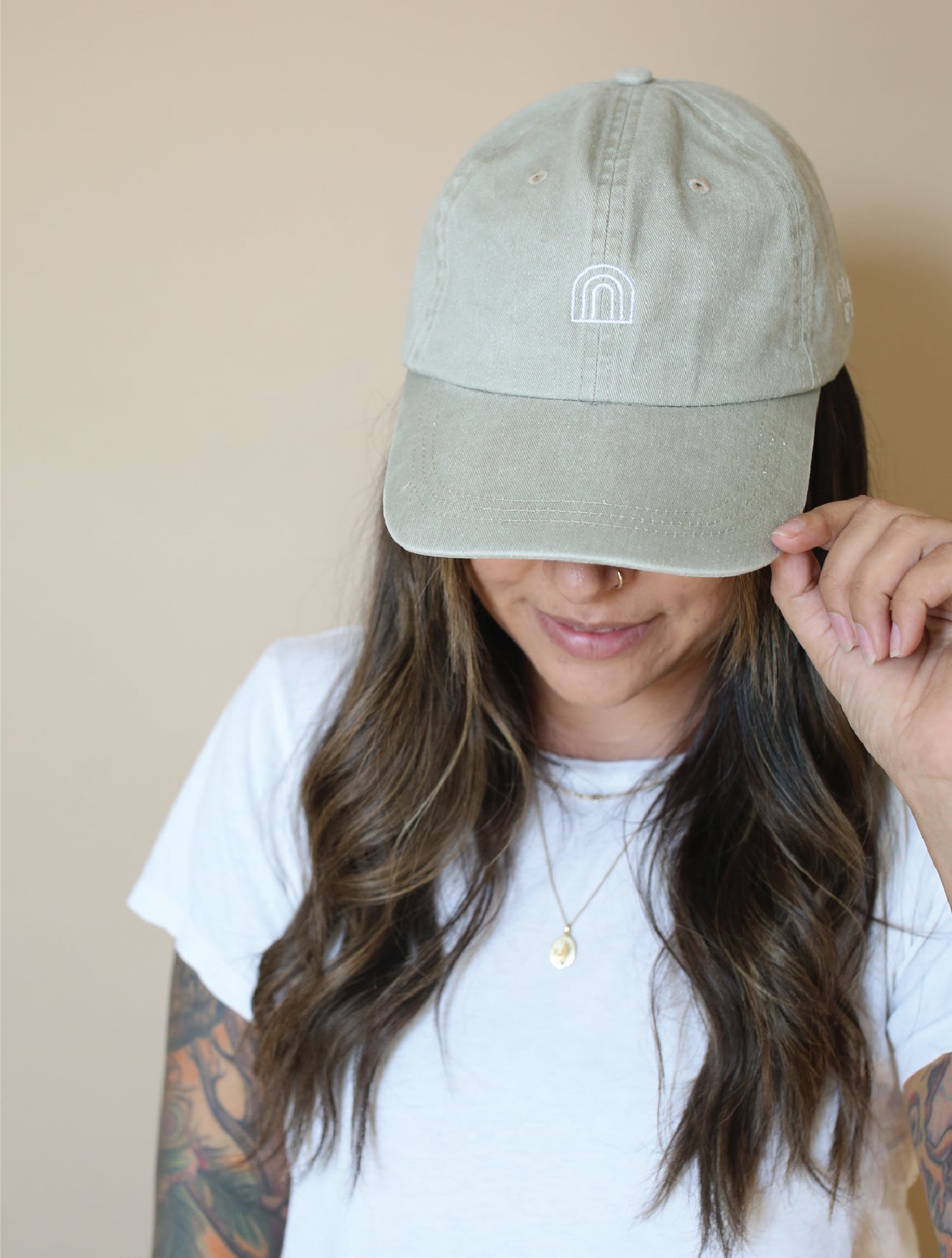 A woman with the wiley baseball hat facing forward so you can see the rainbow logo on the front of the hat