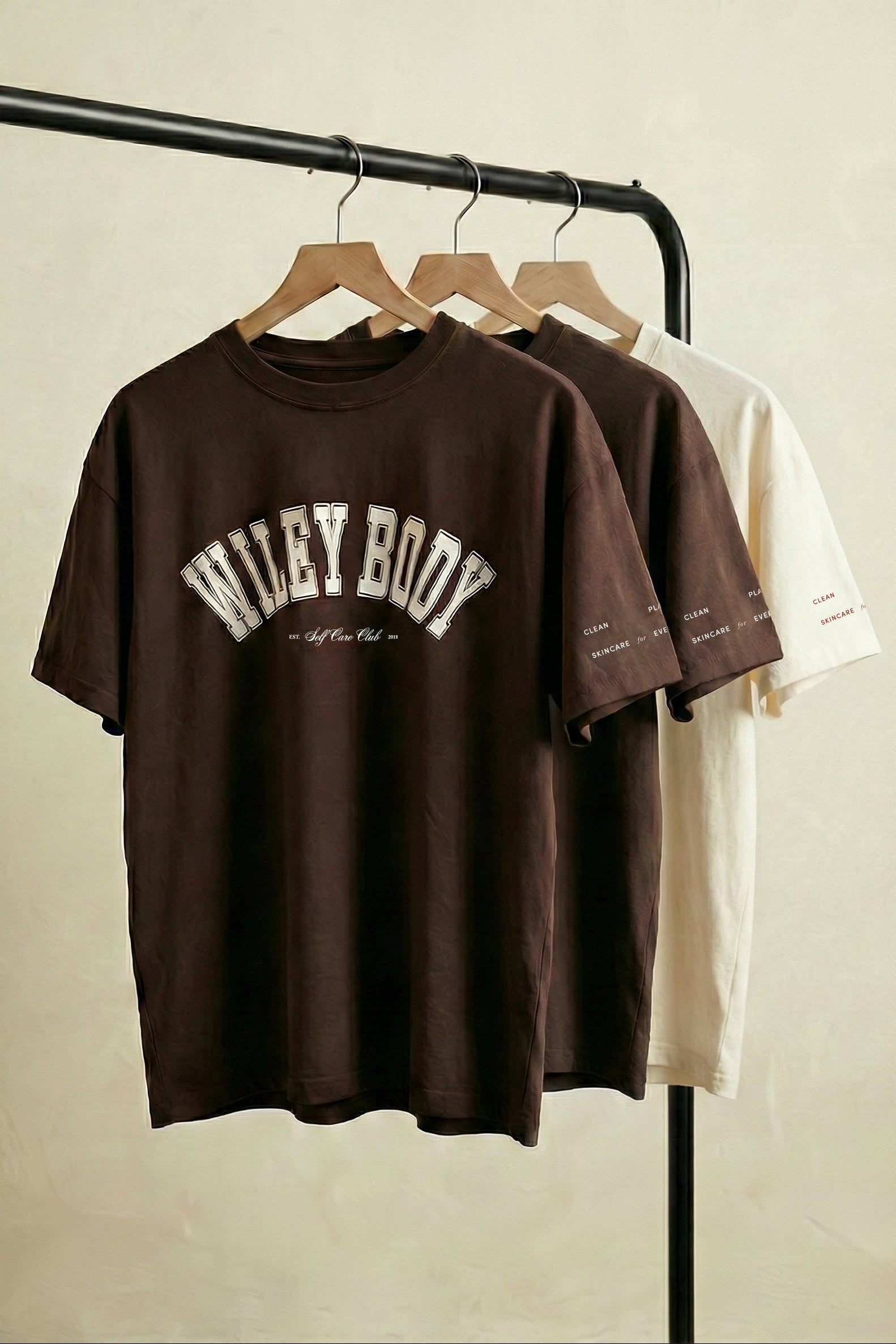 Brown and white t-shirts on hangers against a plain background
